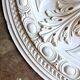 Rosette on white background, decorated with scrolls and beaded frieze ⌀ 61 cm