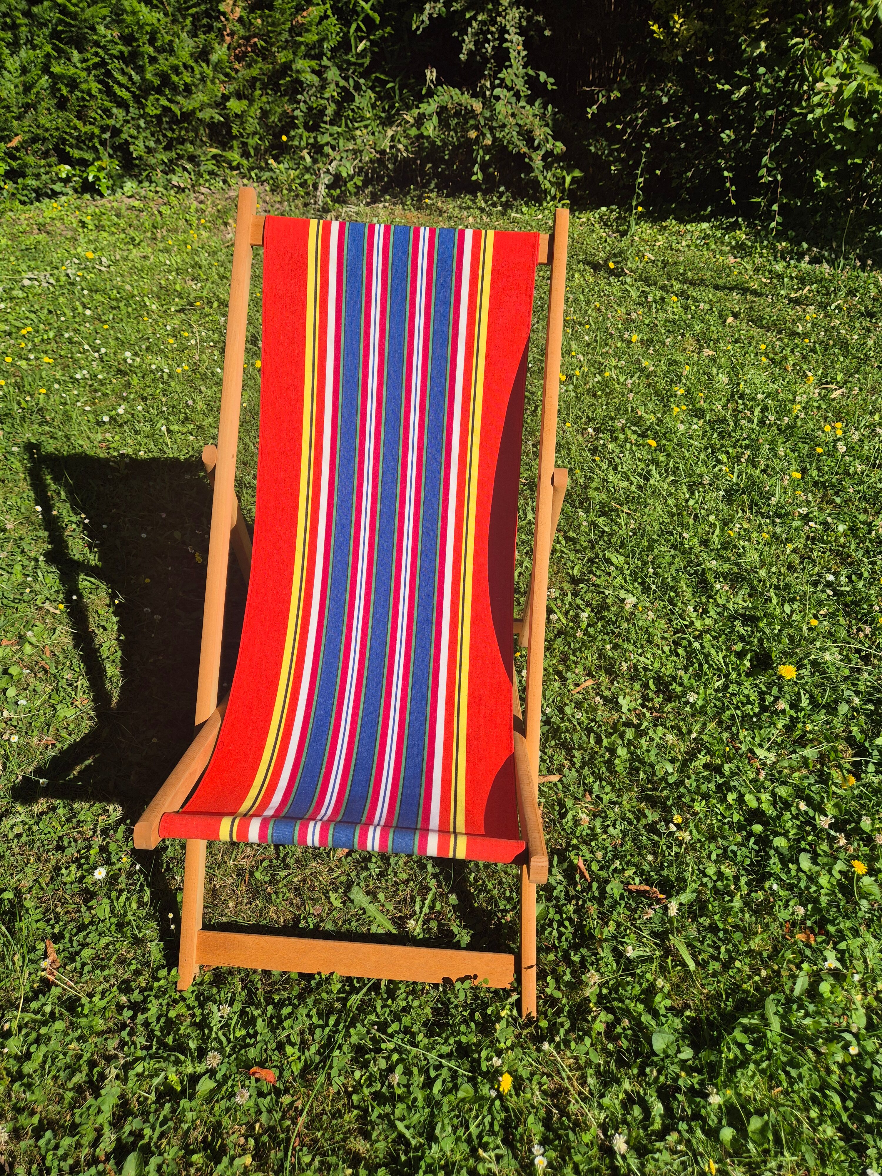 vintage wooden deck chair with red, blue, and yellow striped fabric