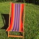 vintage wooden deck chair with red, blue, and yellow striped fabric