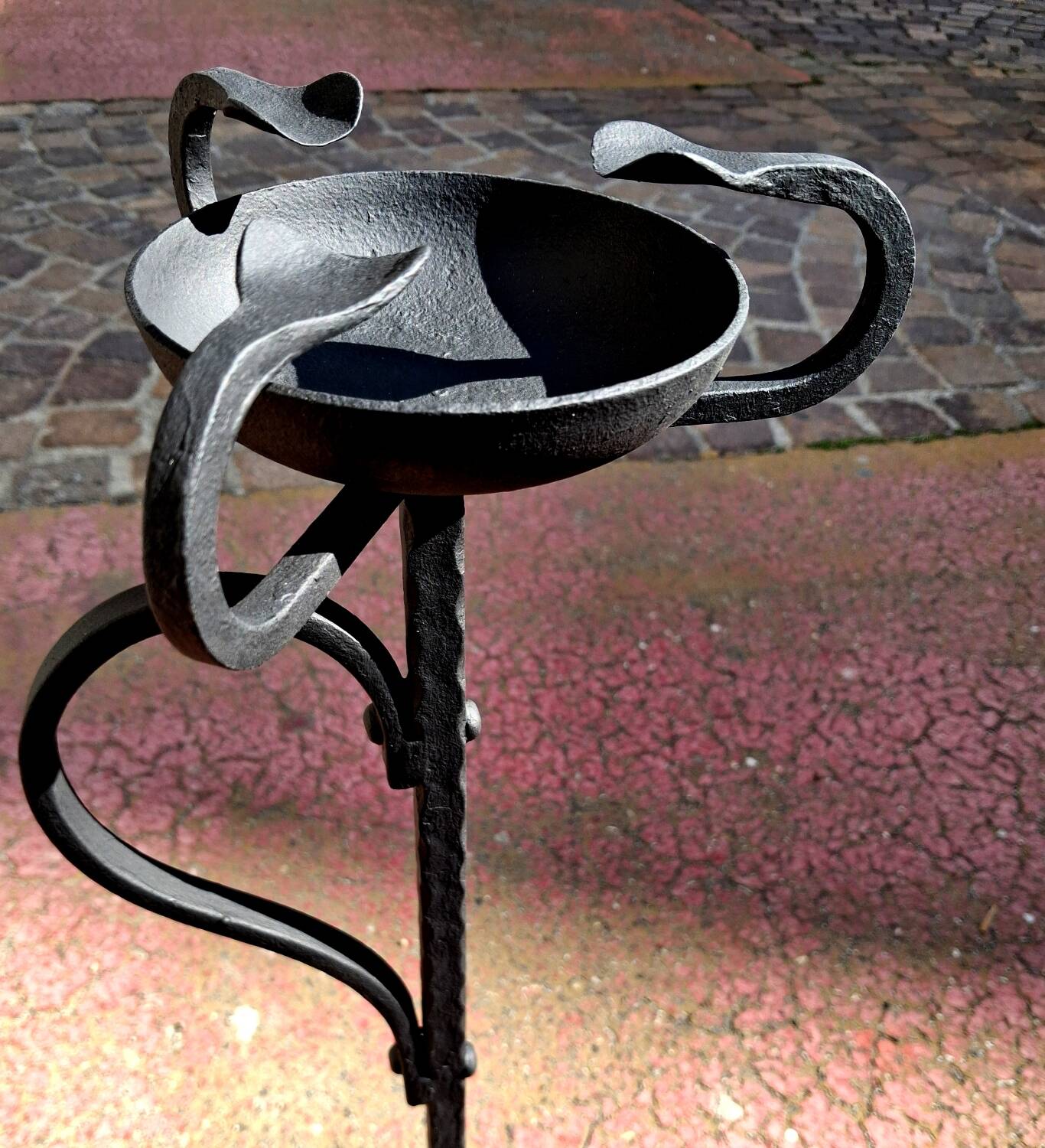 Old ashtray on twisted hammered wrought iron legs, vintage decor.