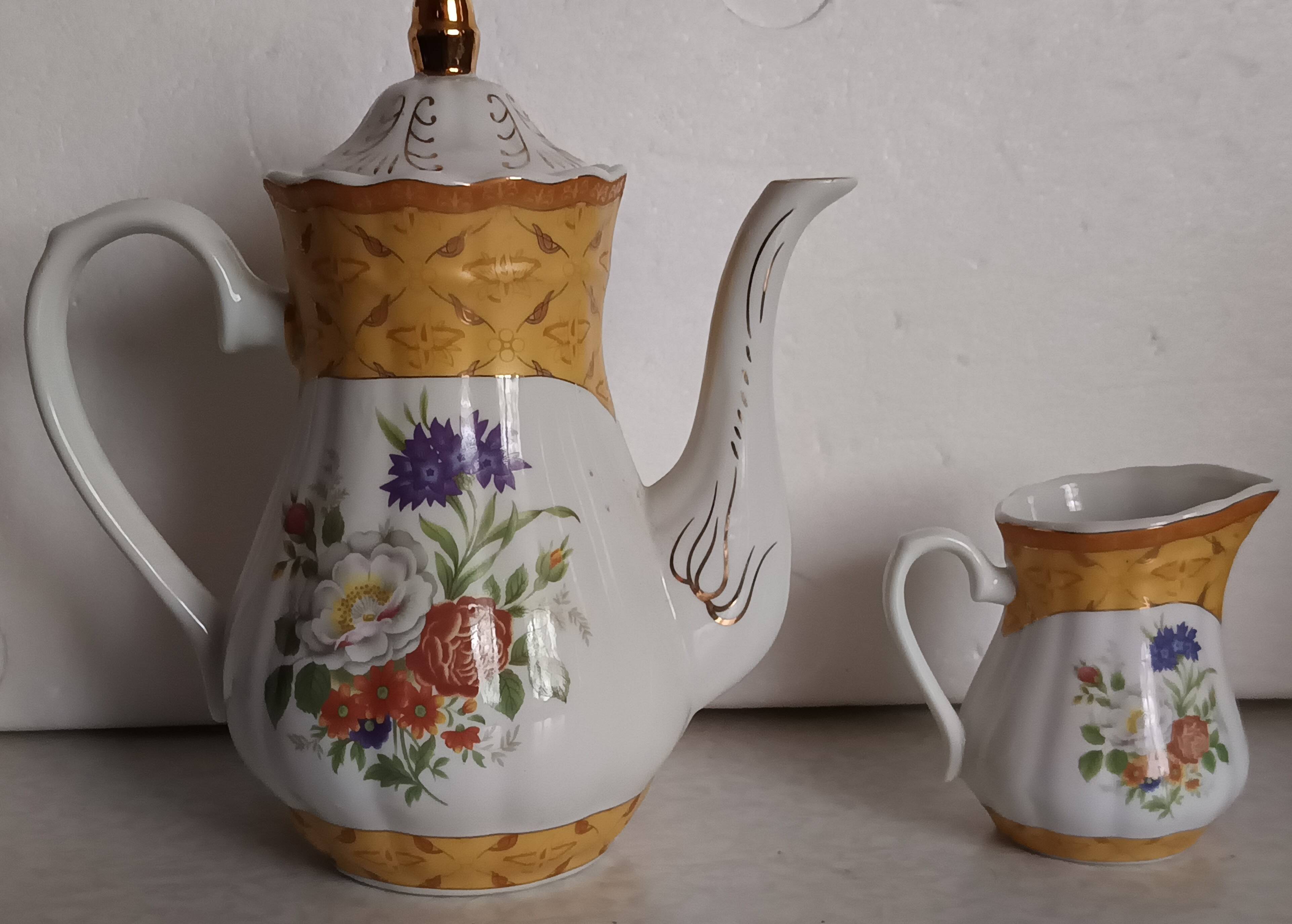 Golden porcelain teapot and coffee pot set with floral design and matching milk jug.