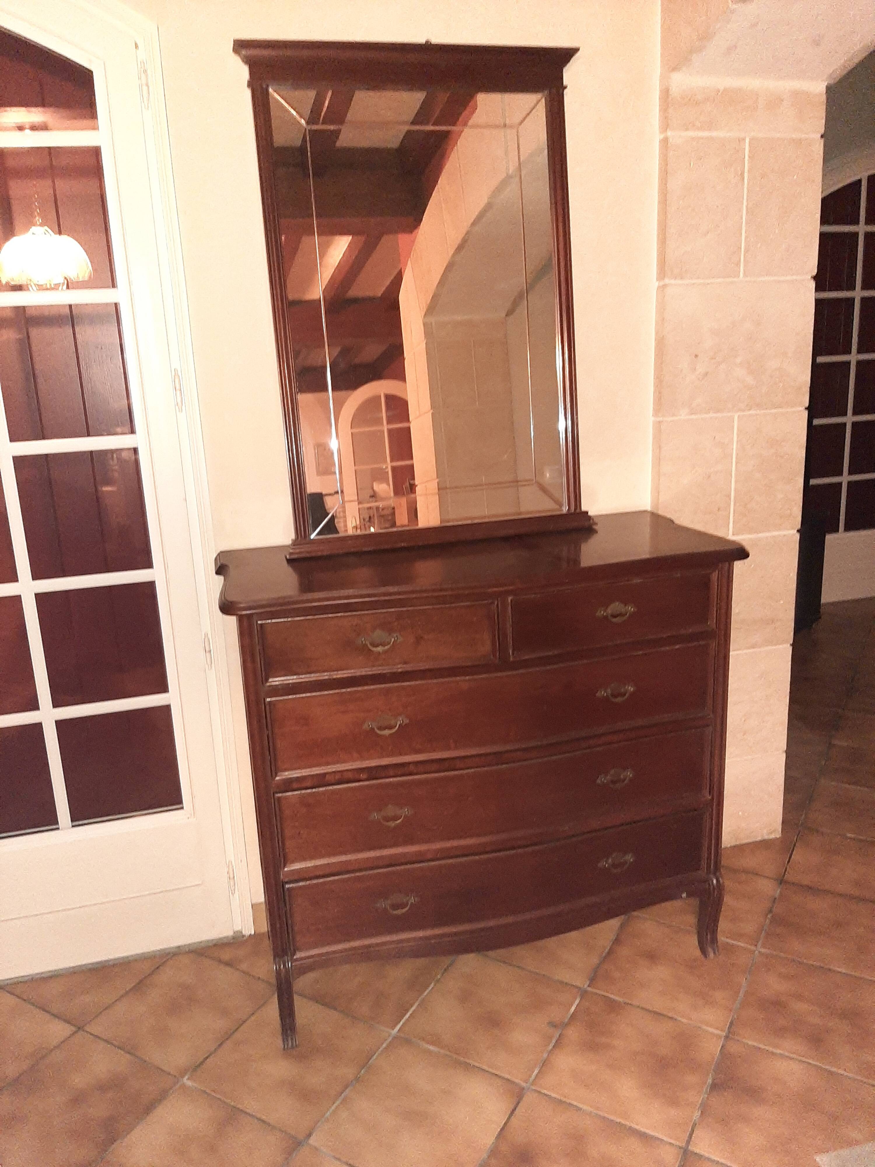 Style set: bevelled mirror and curved wooden chest of drawers.