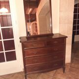 Style set: bevelled mirror and curved wooden chest of drawers.