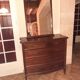 Style set: bevelled mirror and curved wooden chest of drawers.