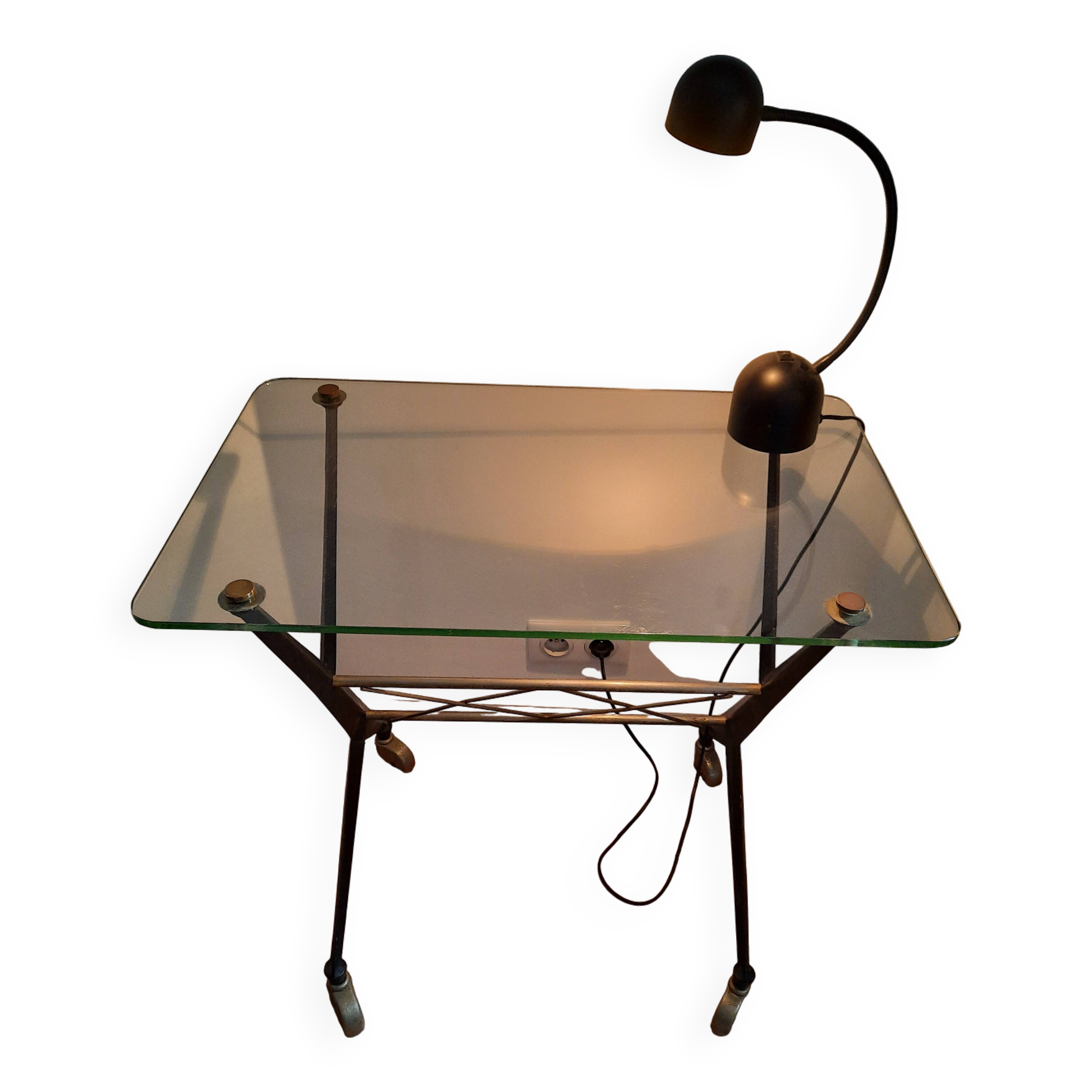 Vintage table with thick glass top and black steel legs with casters.