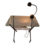 Vintage table with thick glass top and black steel legs with casters.