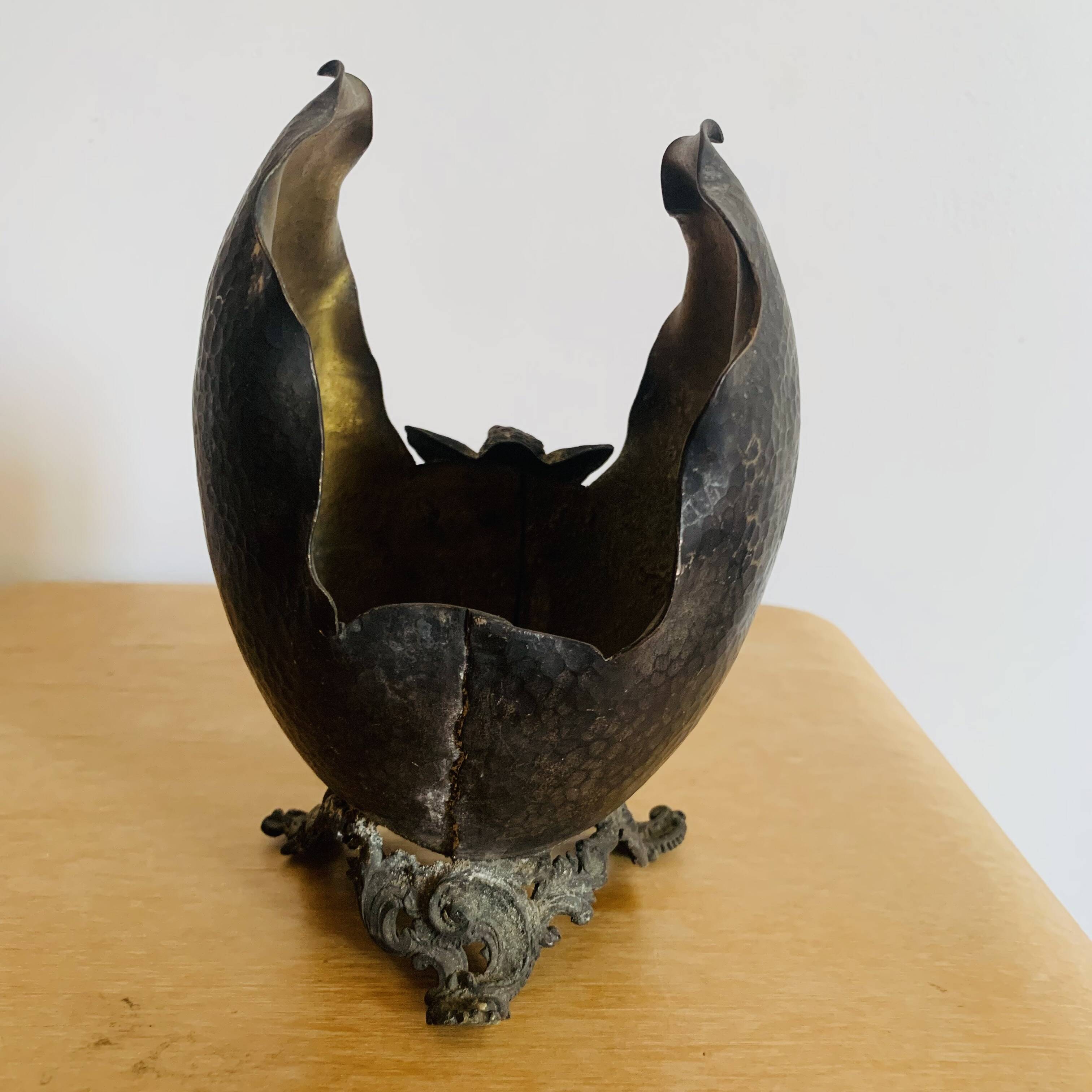 Antique decorative cup in hammered metal with putto design.