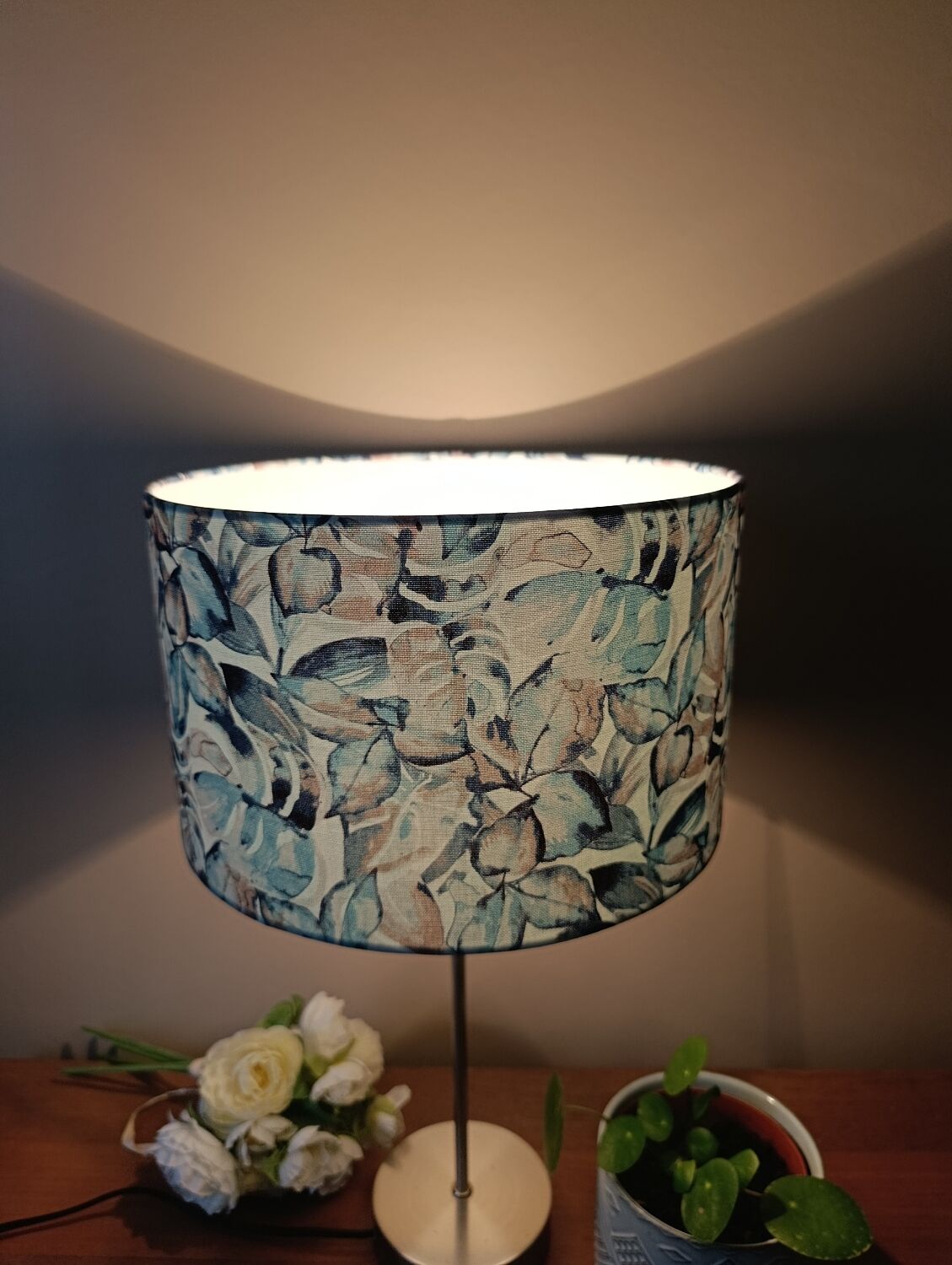 Table lamp with chrome stem, tropical plant shade.