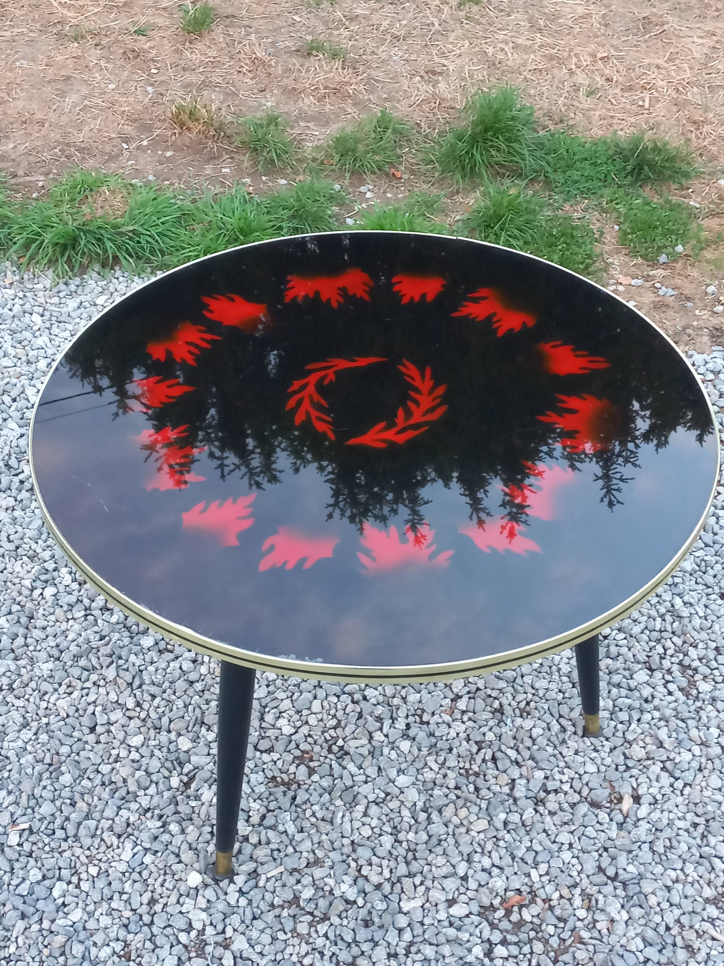 Vintage coffee table with glass top and tripod legs in blackened wood from the 1960s.