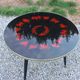 Vintage coffee table with glass top and tripod legs in blackened wood from the 1960s.