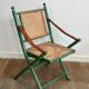 Paire de chaises safari pliantes façon faux-bambou patiné, dossiers et assises cannées et repose-bras en cuir