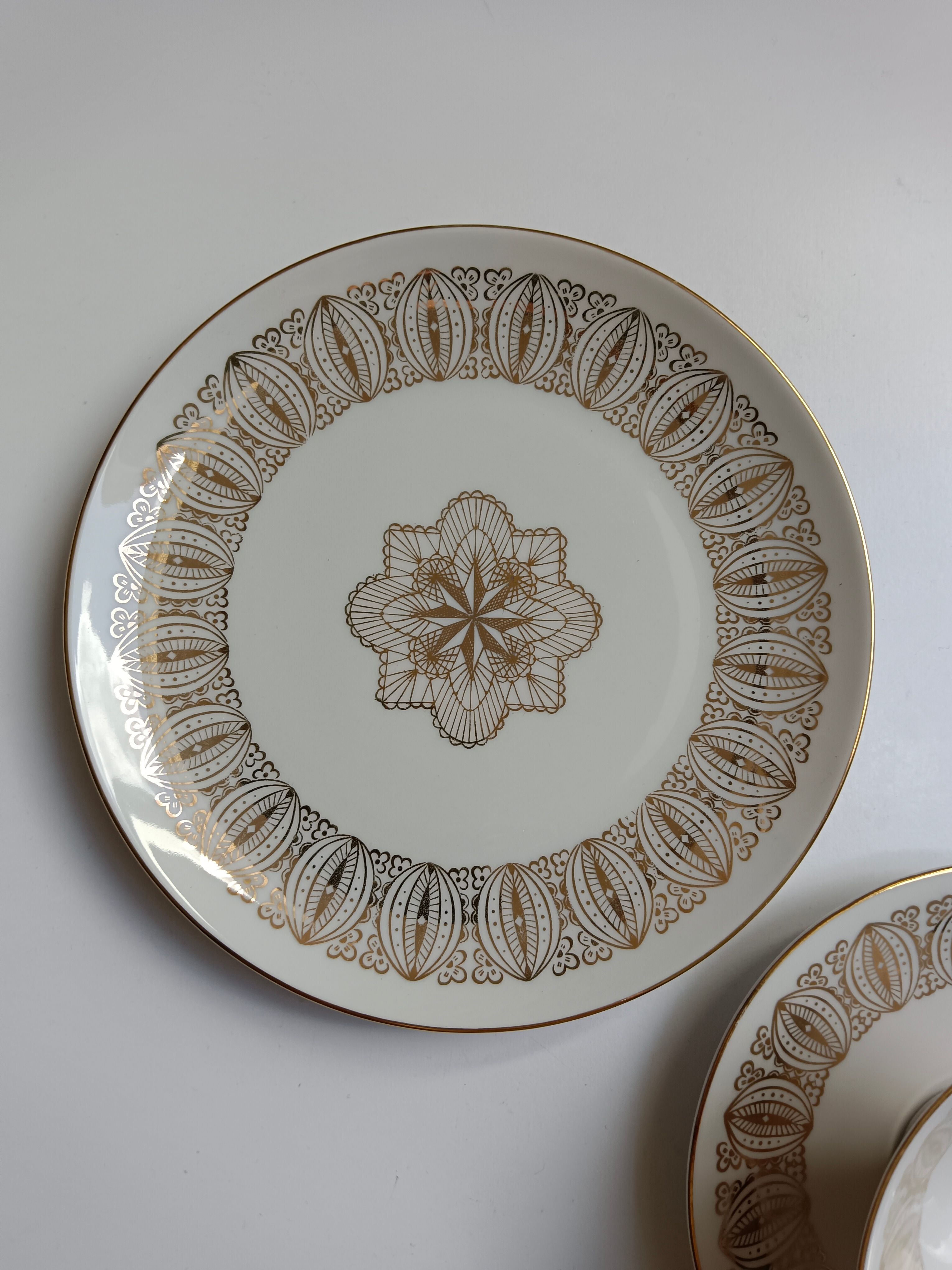 Solitaire tea cup, saucer, and dessert plate in white and gold.
