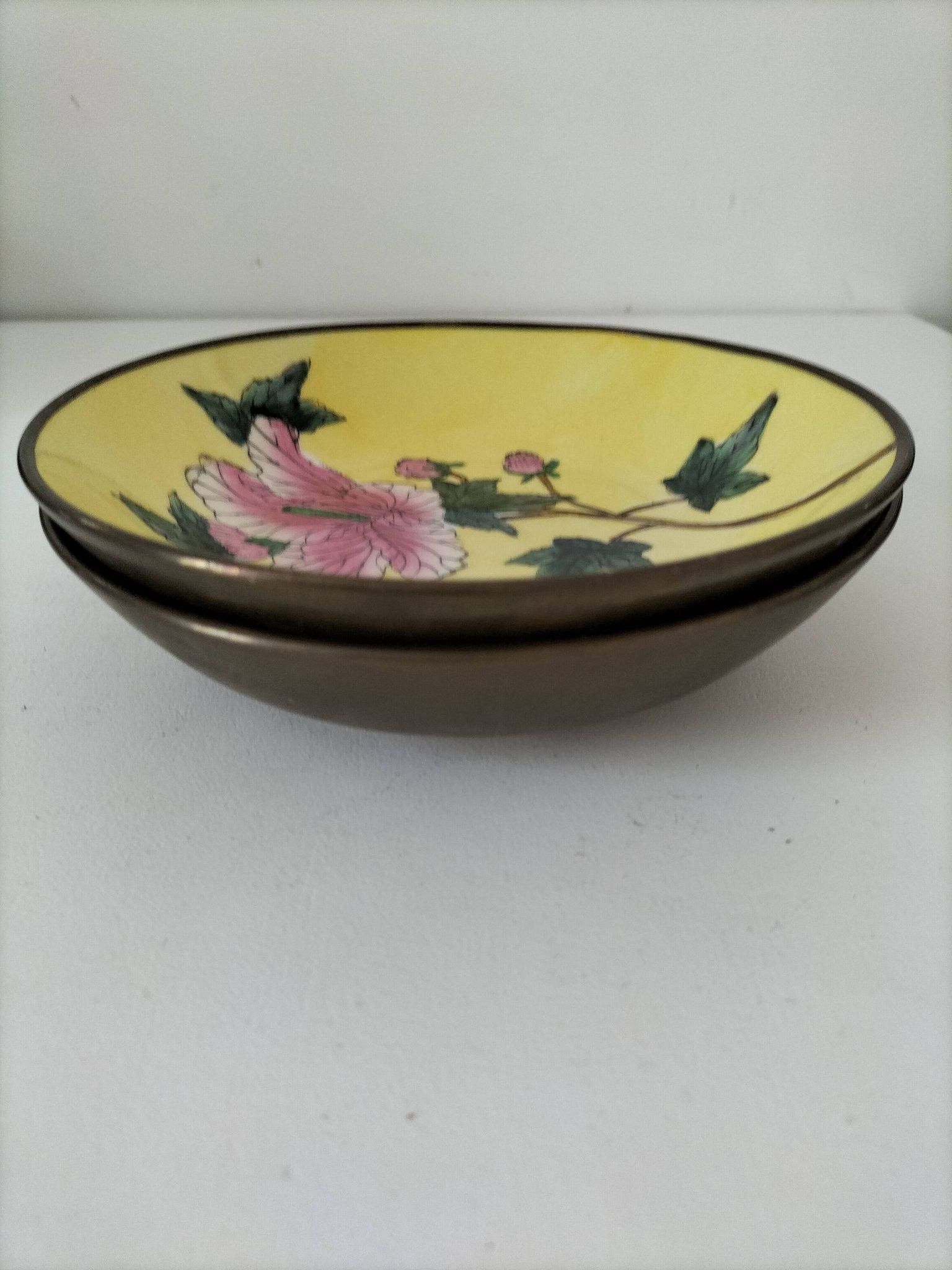 A pair of vintage Chinese decorative plates with floral designs on a yellow background.