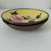 A pair of vintage Chinese decorative plates with floral designs on a yellow background.