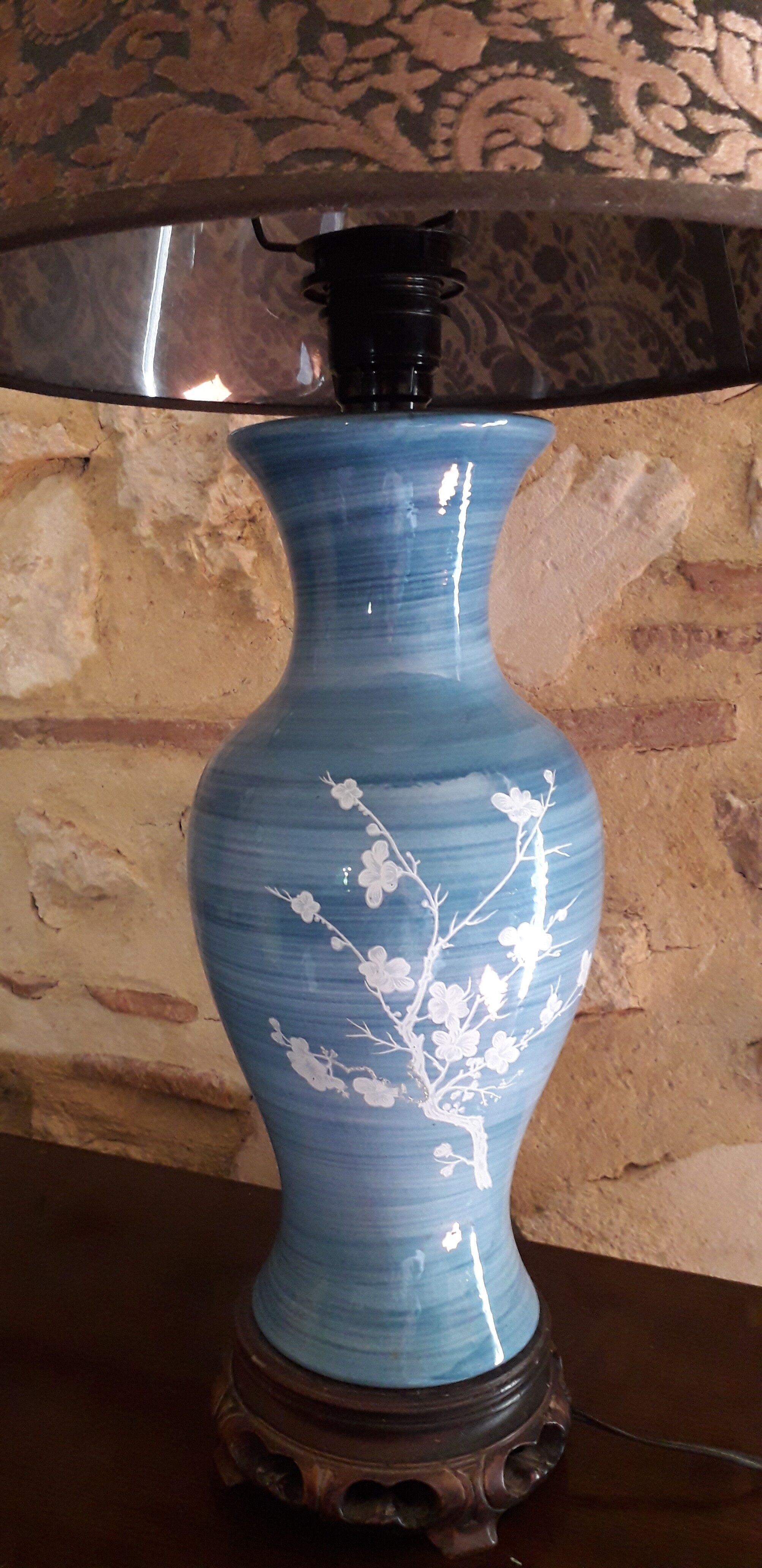 Large blue porcelain lamp with white flowers (cherry blossoms) on wooden stand.