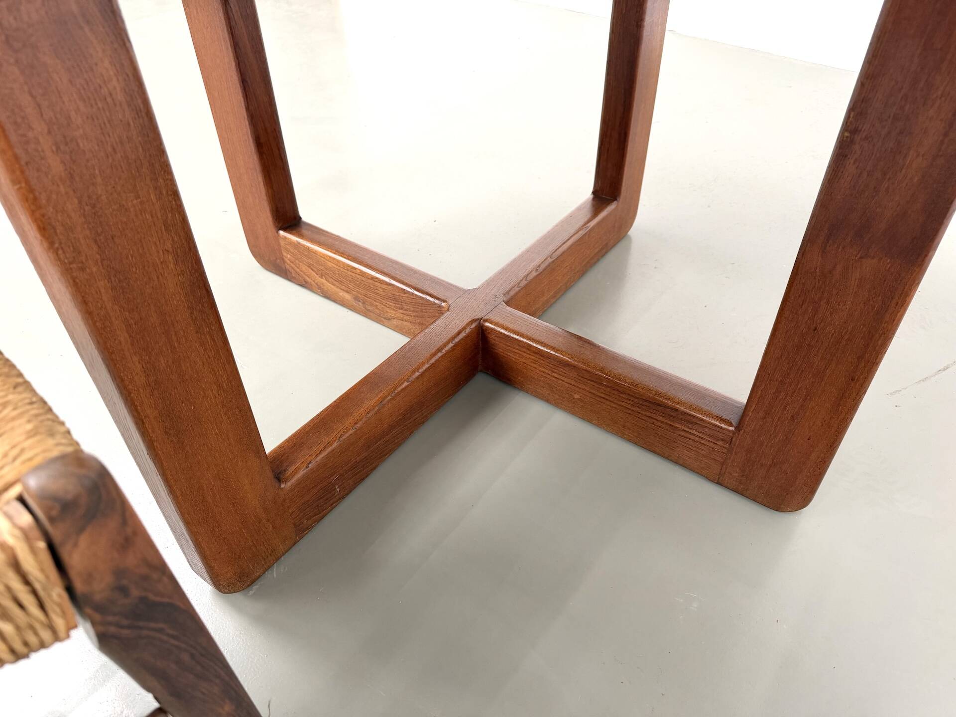 Modernist round table in solid elm, crossed legs.