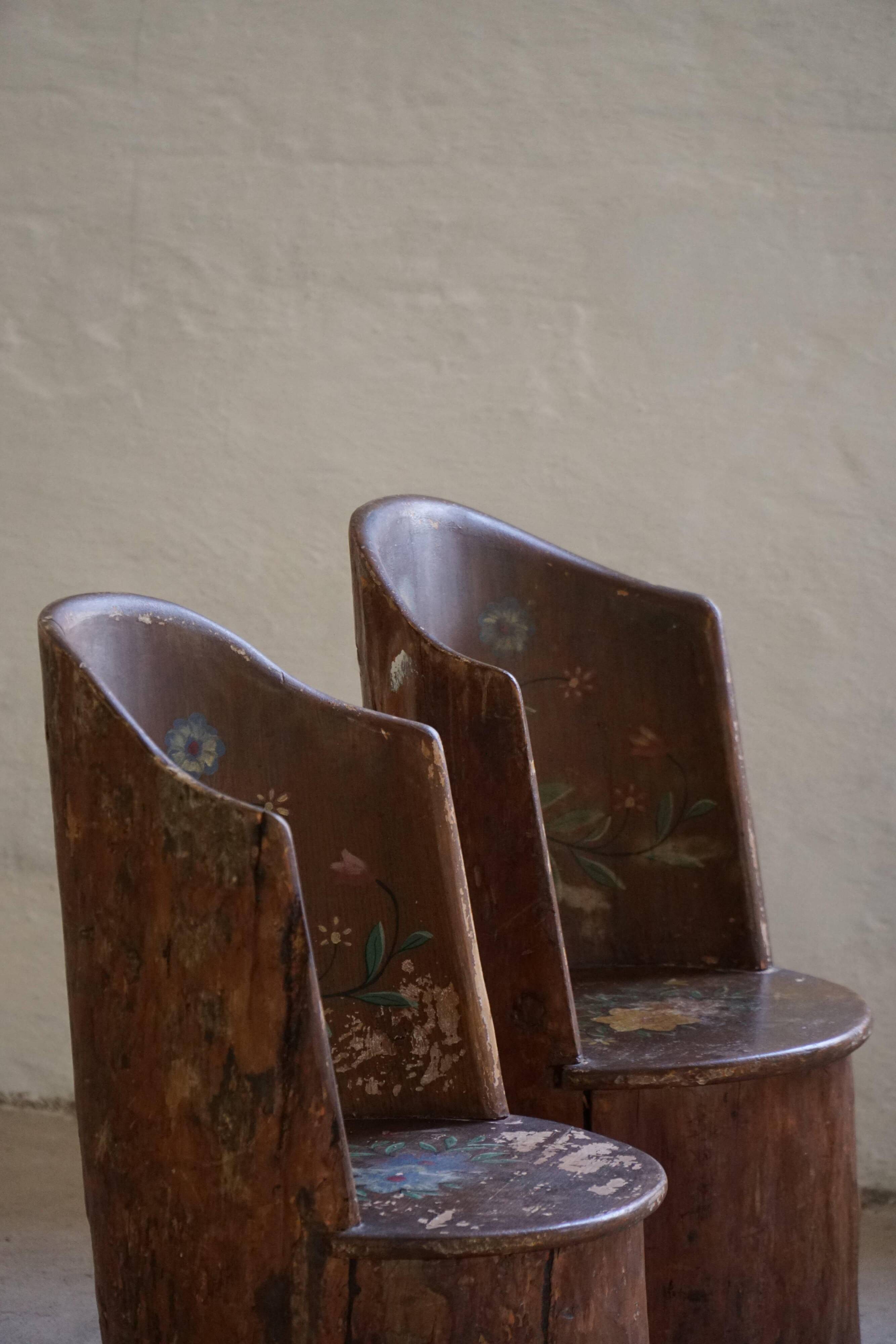Pair of Swedish folk art stump chairs, decorated with painted floral motifs, late 19th century.