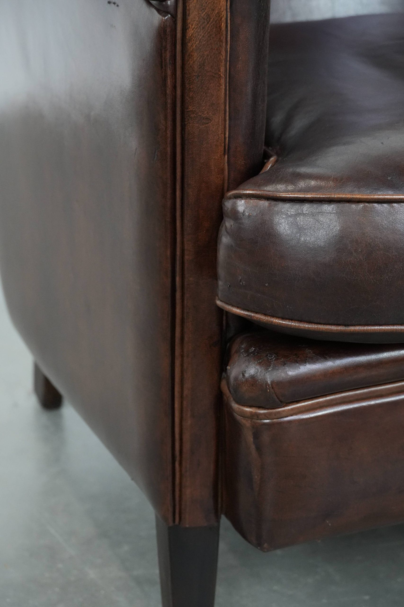 Dark brown vintage club armchair in English style made of sheepskin leather