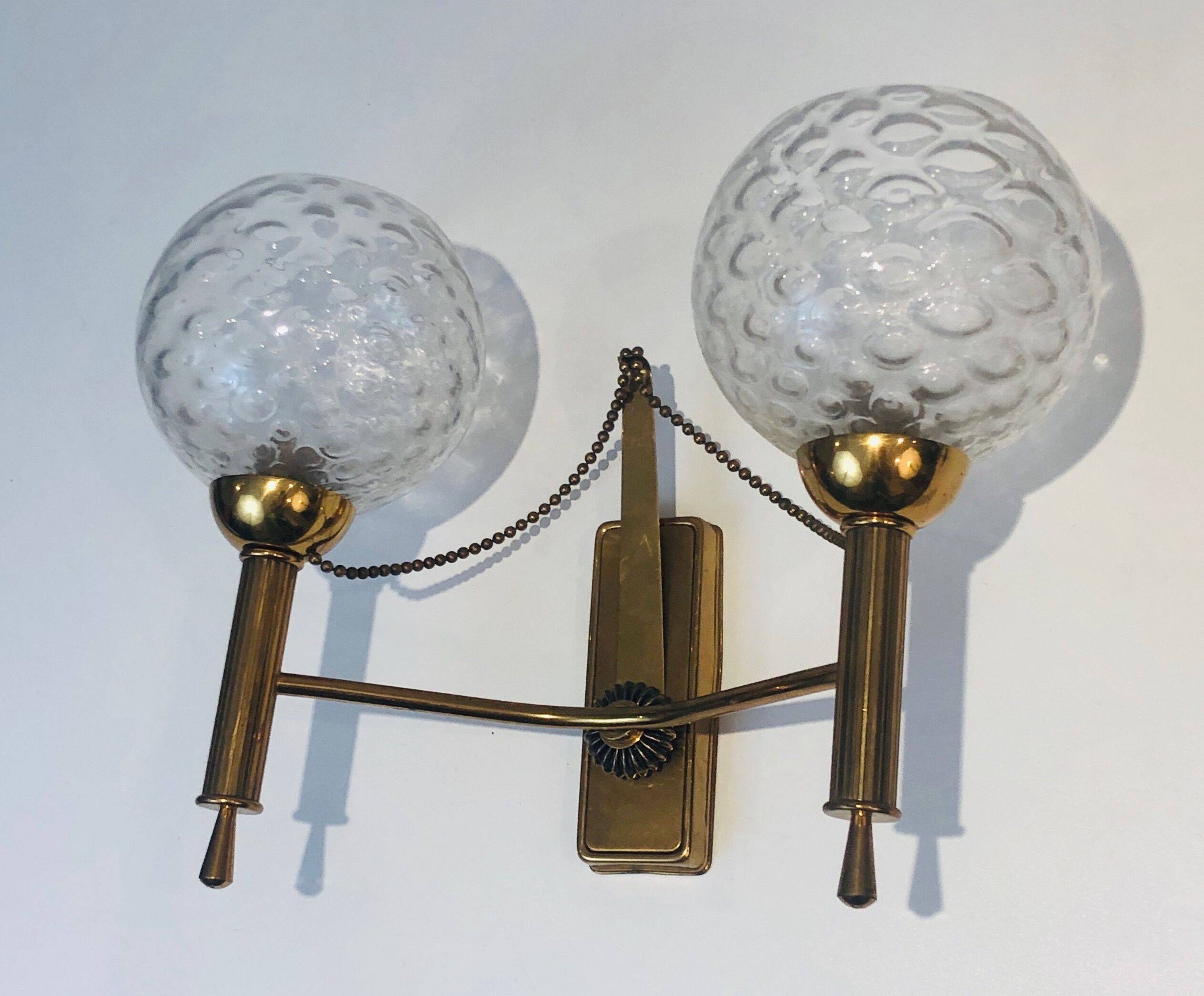 Pair of brass wall lights with glass globes. Around 1970.