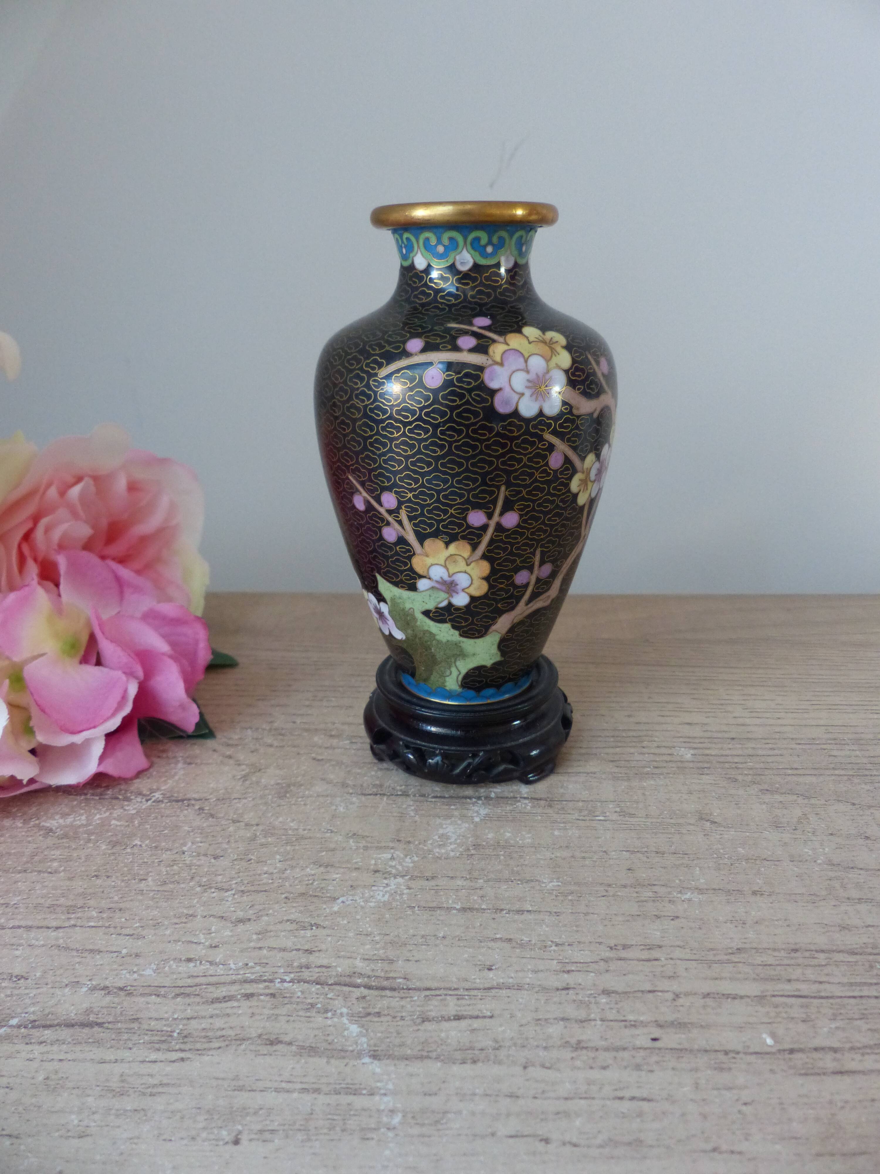 Small black cloisonné vase decorated with yellow and pink cherry blossoms, vase on wooden base