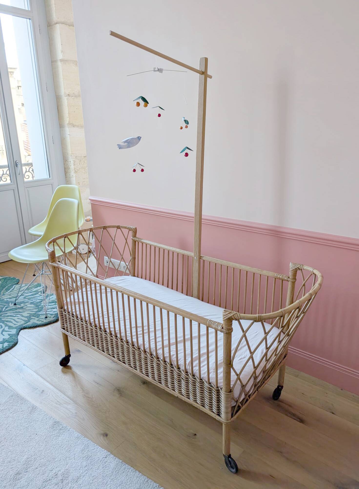 Newly refurbished rattan baby crib, with an oak arrow for a mobile.