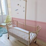 Newly refurbished rattan baby crib, with an oak arrow for a mobile.
