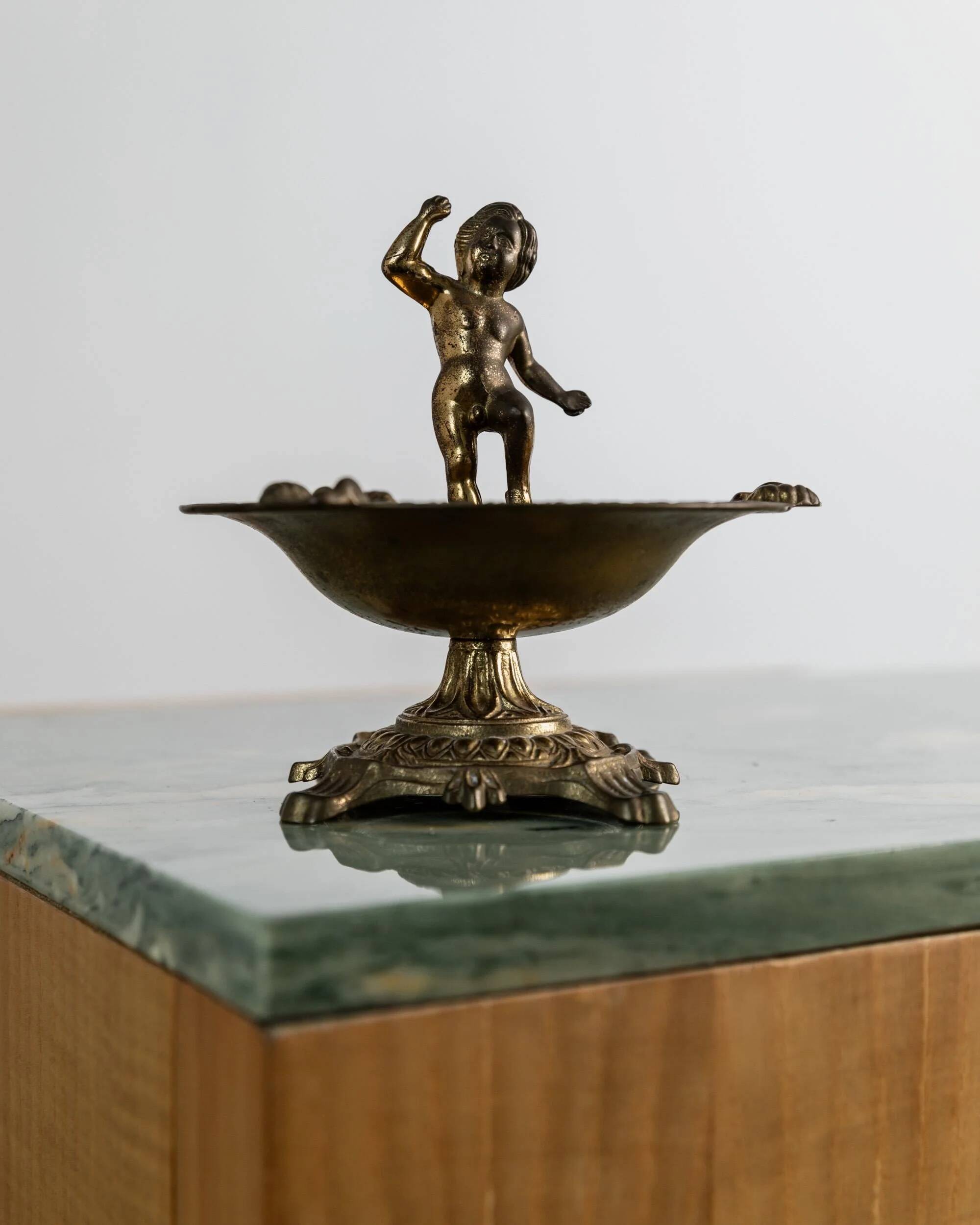 Vintage brass ashtray from the 1940s with a nude boy figurine on a footed base.