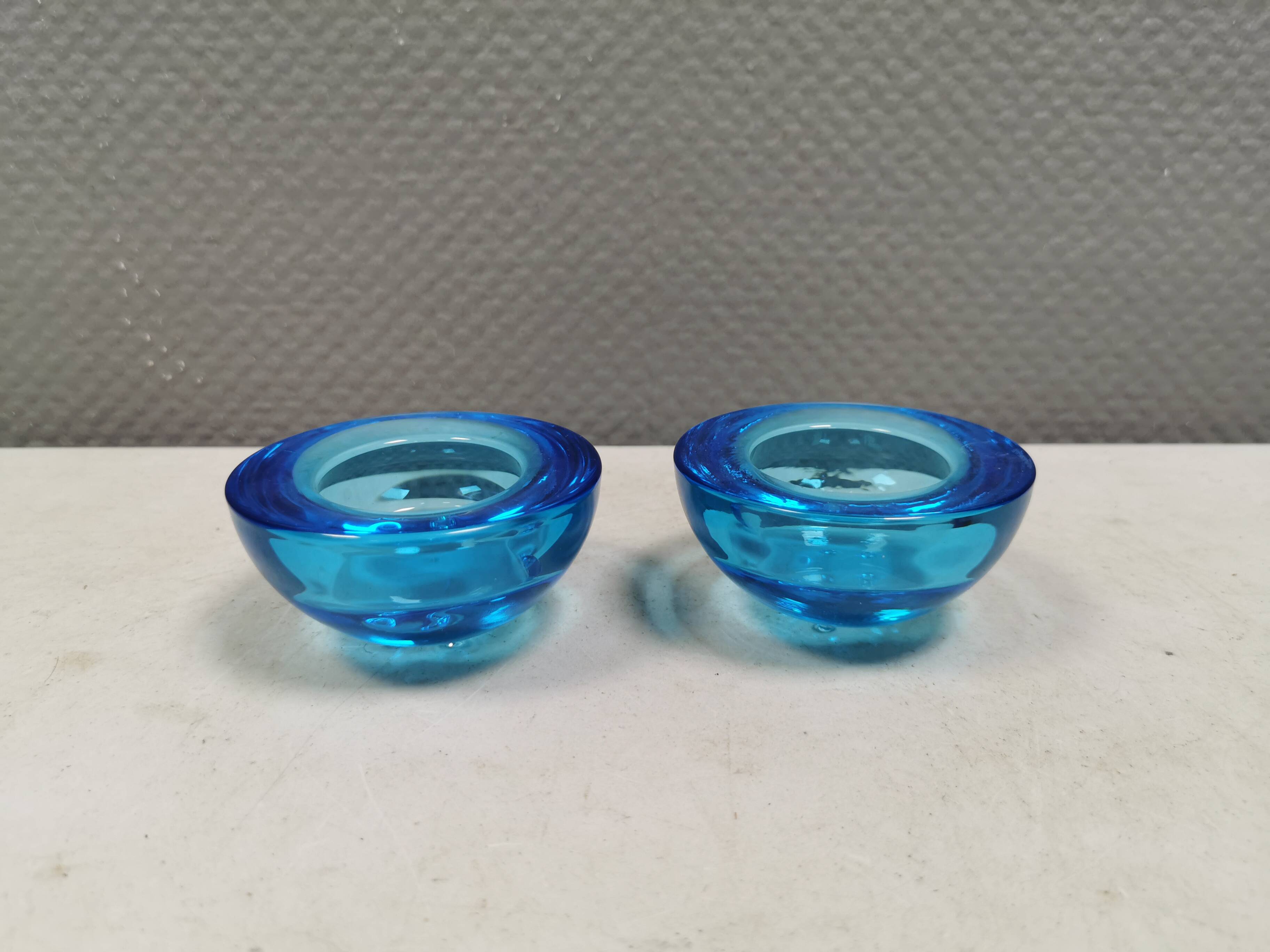 A set of iitalla candle holders in blue transparent glass.