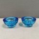 A set of iitalla candle holders in blue transparent glass.
