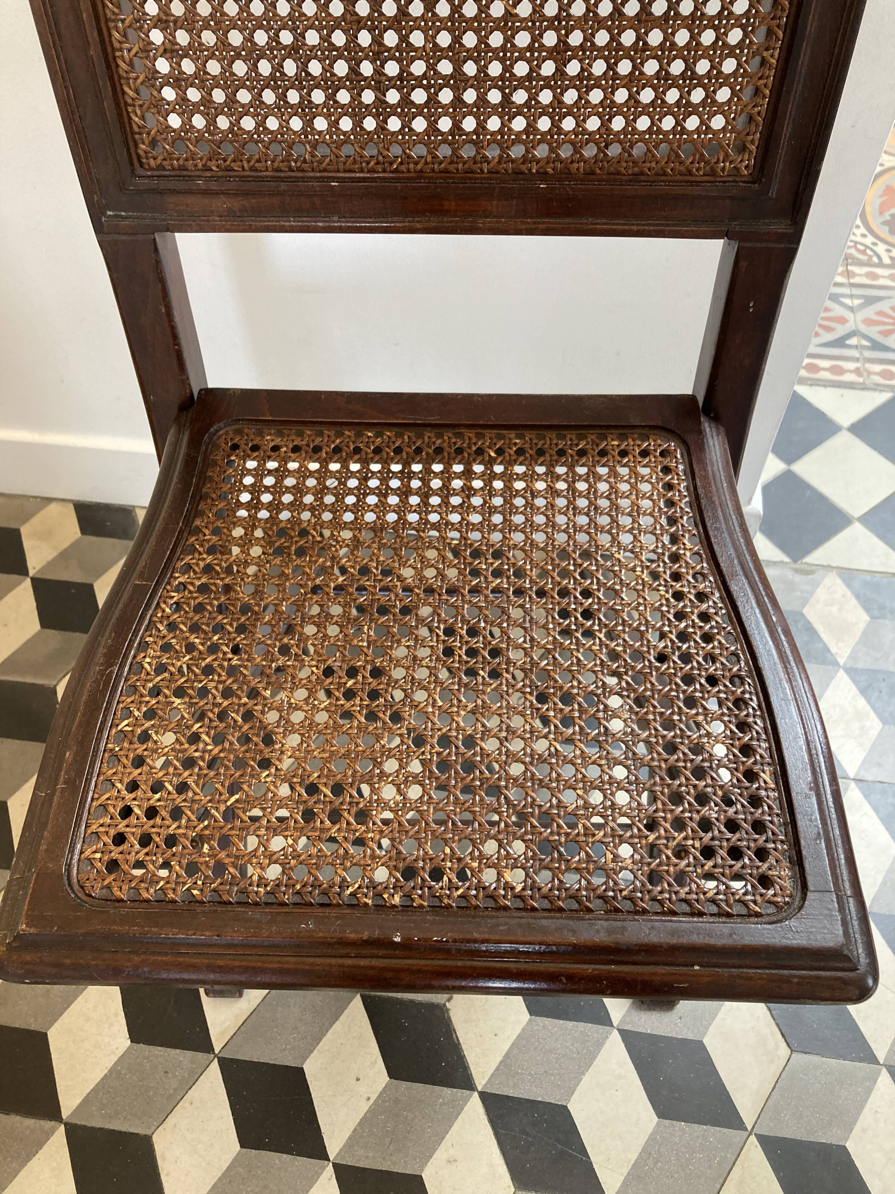 Vintage folding chair with cane seat in dark mahogany wood