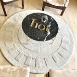 Round ecru rug with geometric relief patterns in wool
