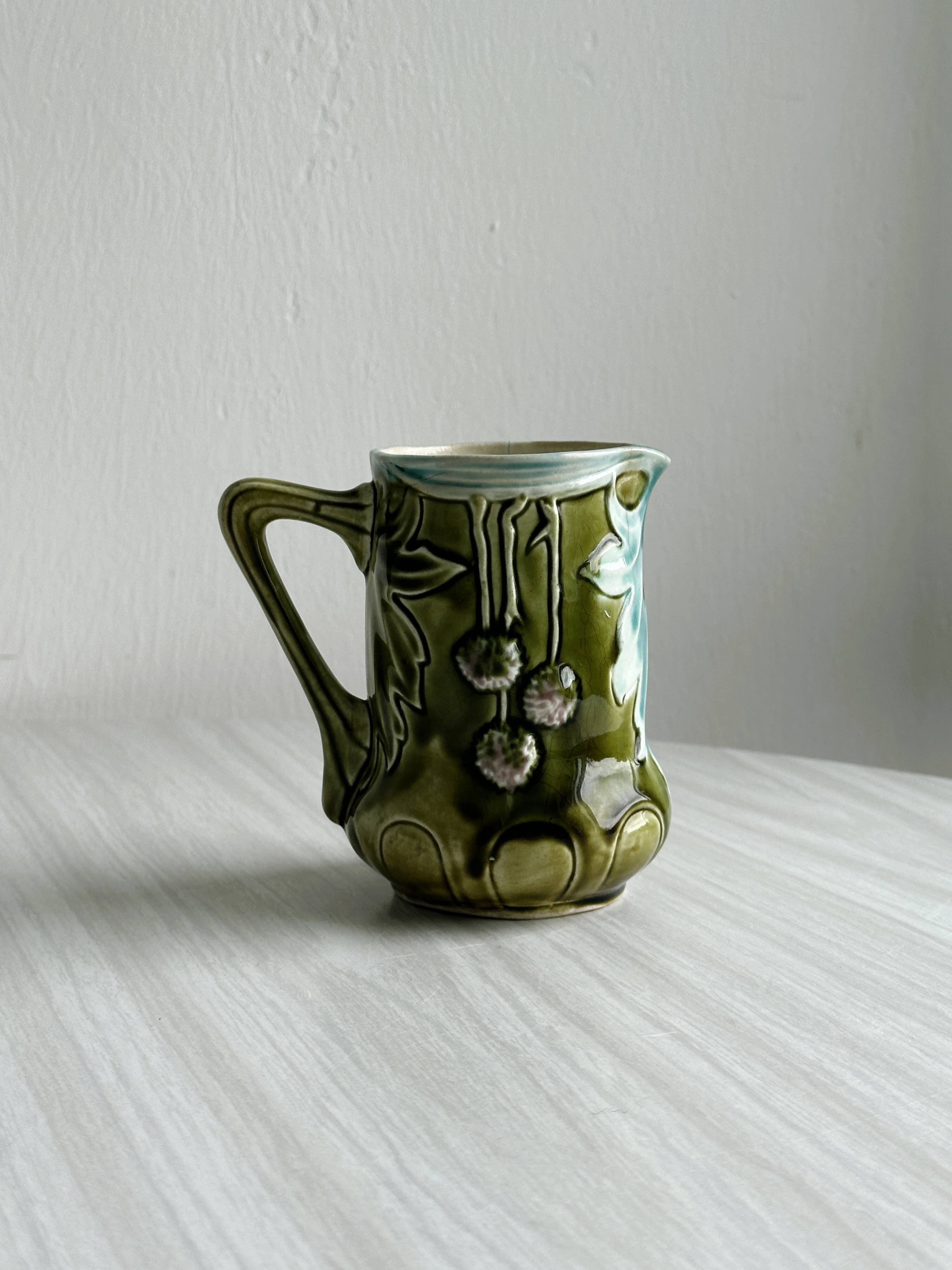 Green slip milk jug with floral patterns.