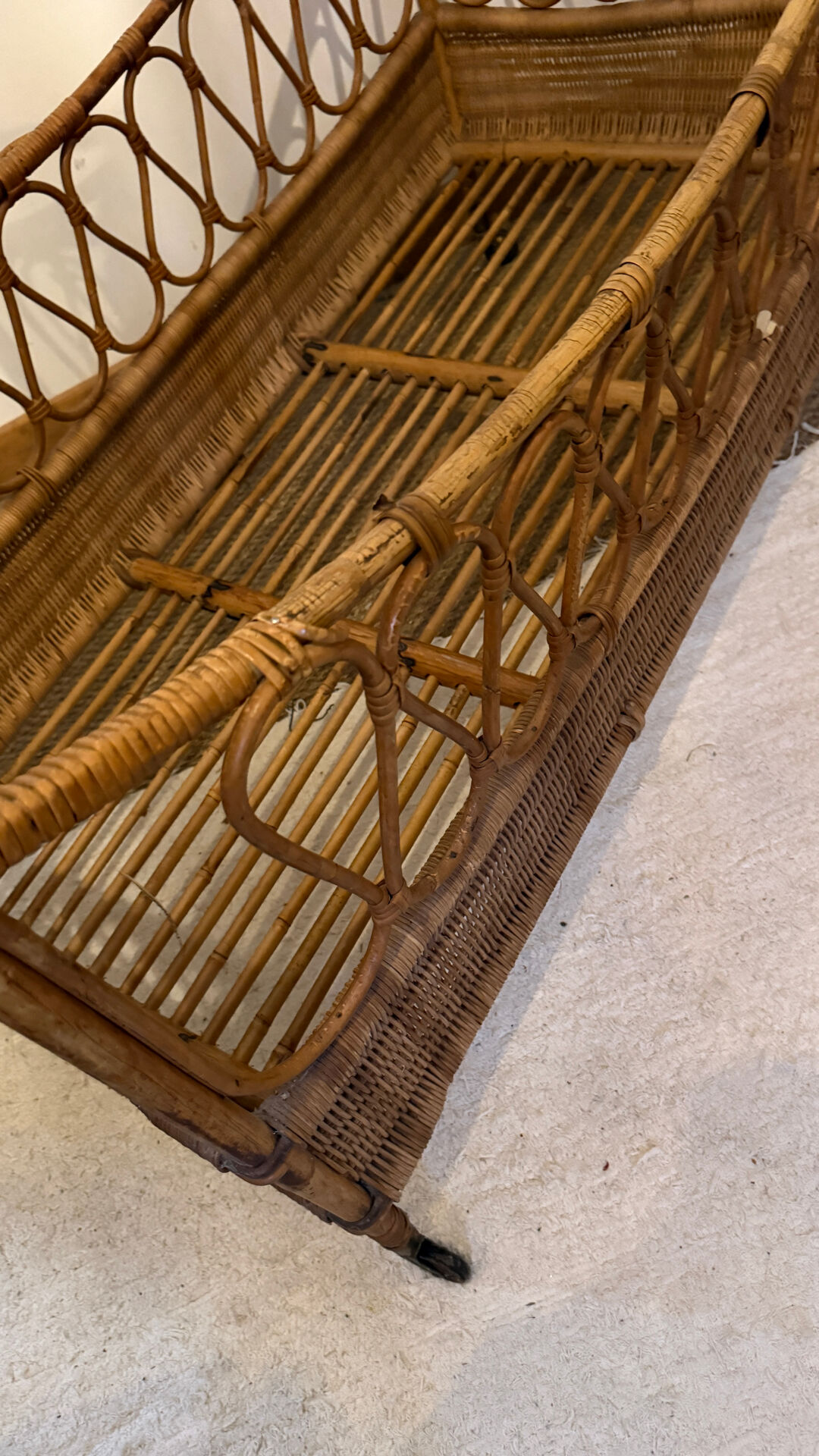 Vintage rattan baby cot on wheels.