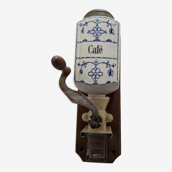 Old wall-mounted coffee grinder in ceramic, metal and wood. Blue flower décor