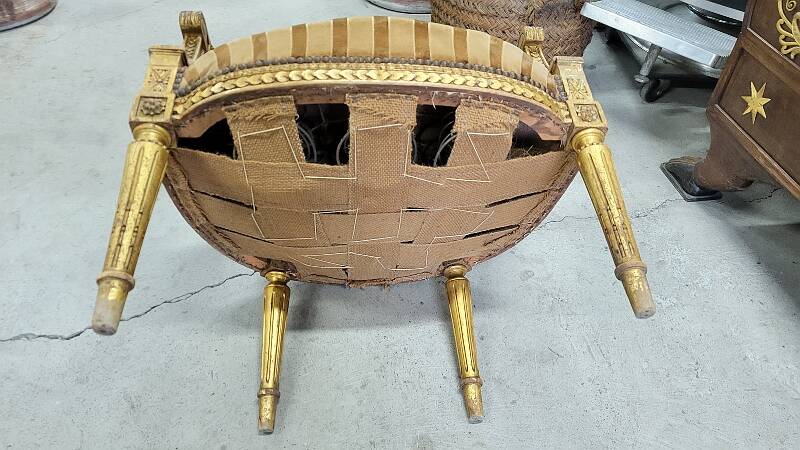 A pair of gilded wooden armchairs in the Louis XVI style.