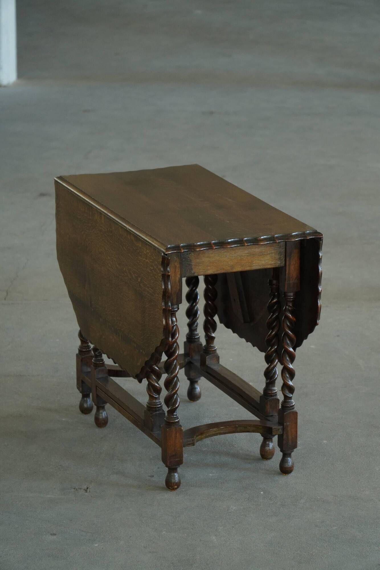 Antique baroque dining table in oak, with folding legs and drop leaves, featuring spiral "barley twist" legs, from the 1920s.