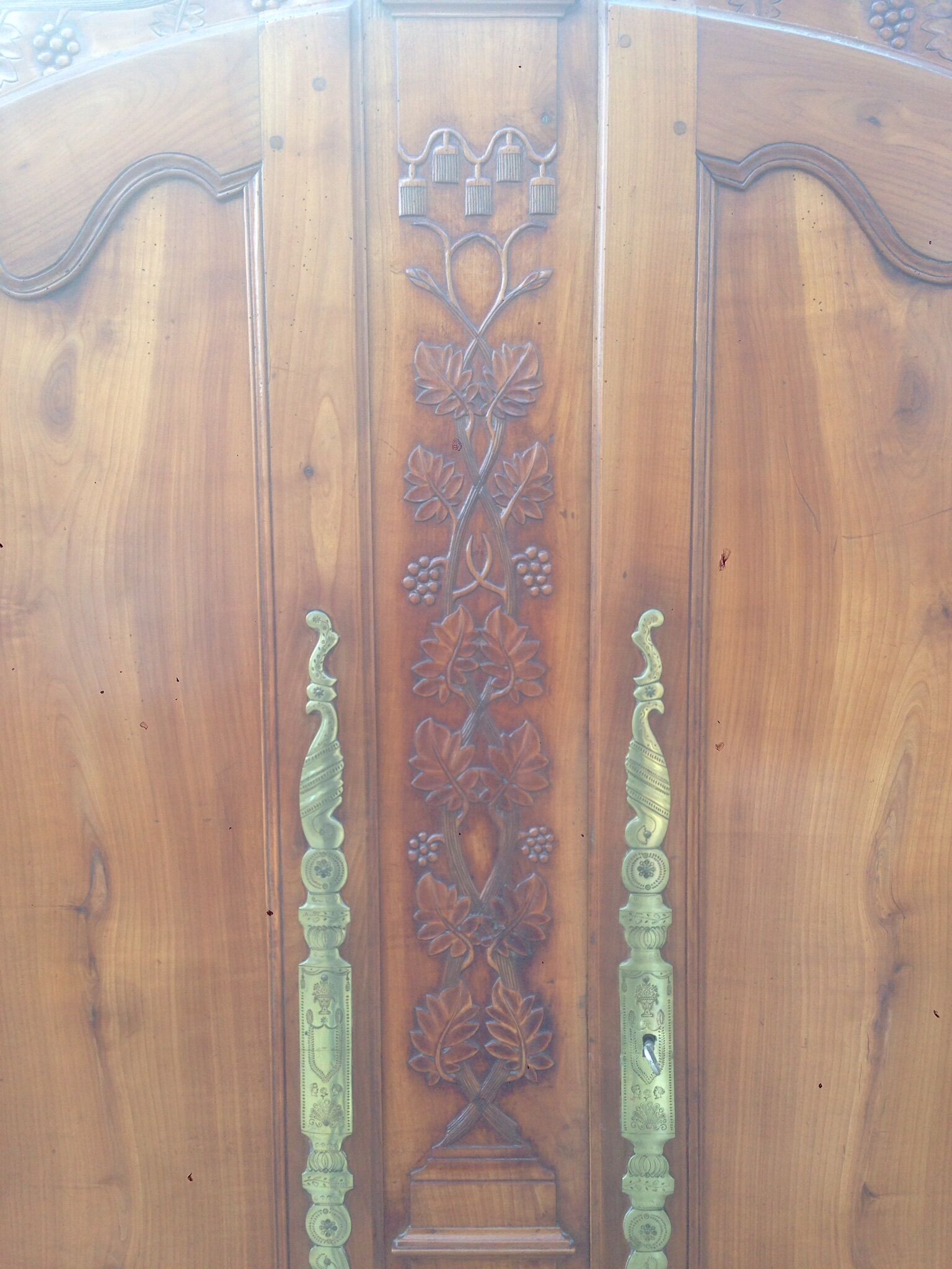 Armoire Louis XV Nantaise sculptée à grappes de raisin, chapeau de gendarme en cerisier fin 19eme.