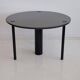 Round dining table in black lacquered metal with a granite top.