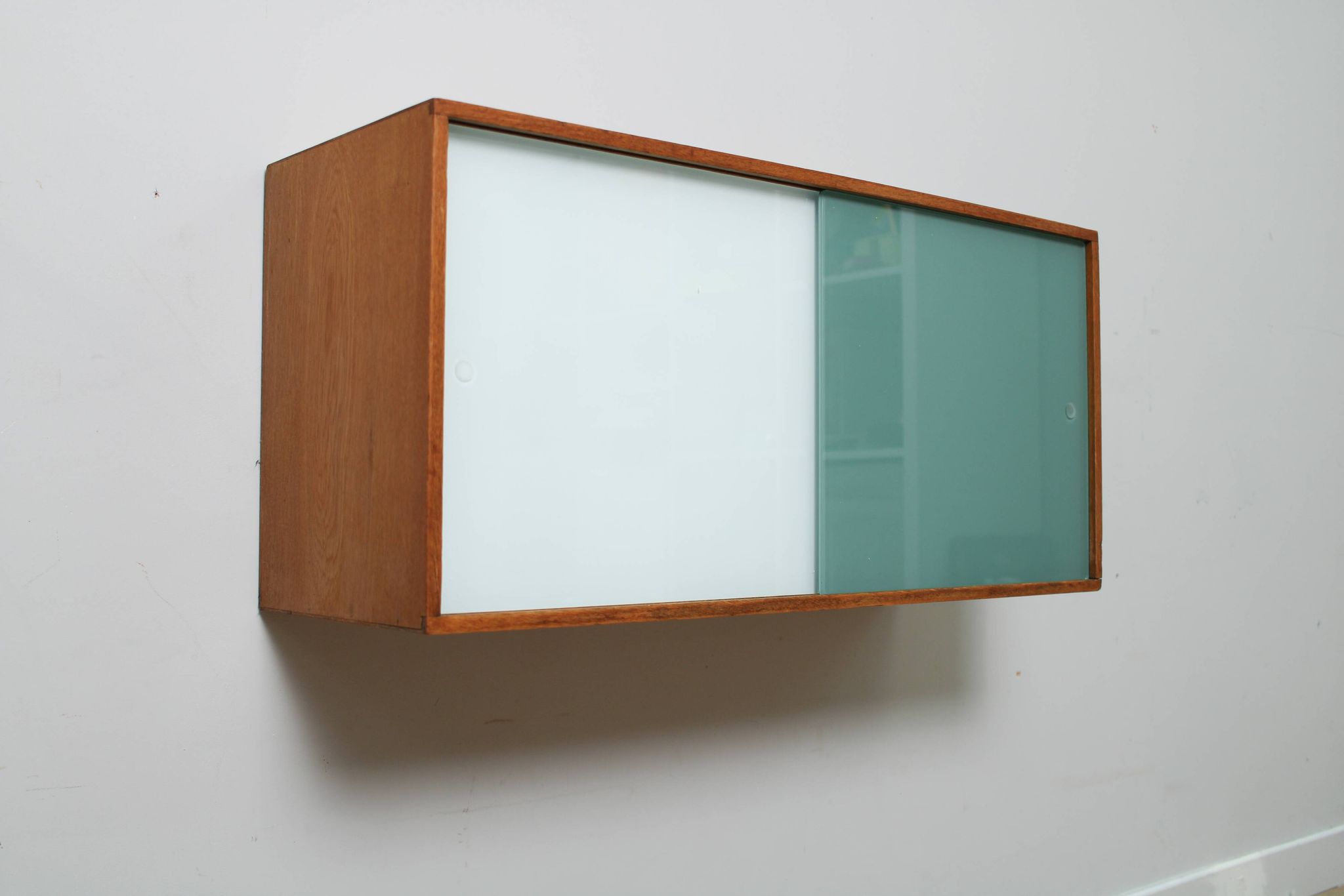 A vintage mid century wall hung bookcase/cabinet with glass sliding doors