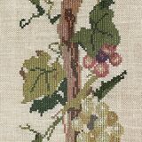 Broderie hollandaise encadrée représentant une vigne avec des raisins, des bouteilles de vin et des paniers