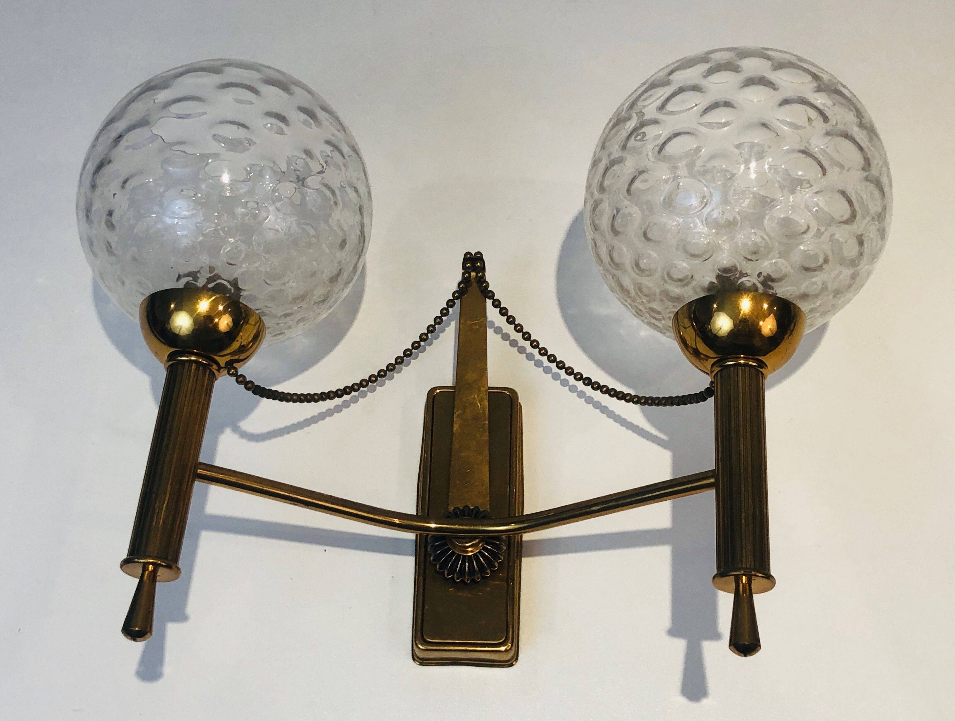 Pair of brass wall lights with glass globes. Around 1970.