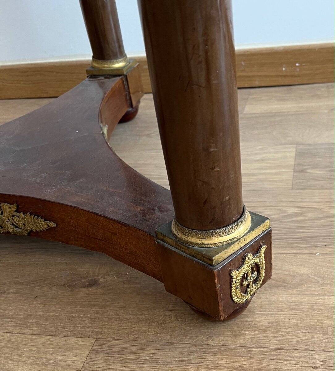 Empire gueridon in mahogany veneer adorned with chiselled and gilded bronze, topped with black marble with a groove.