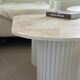 Oval coffee table duo travertine and white fluted wooden legs.