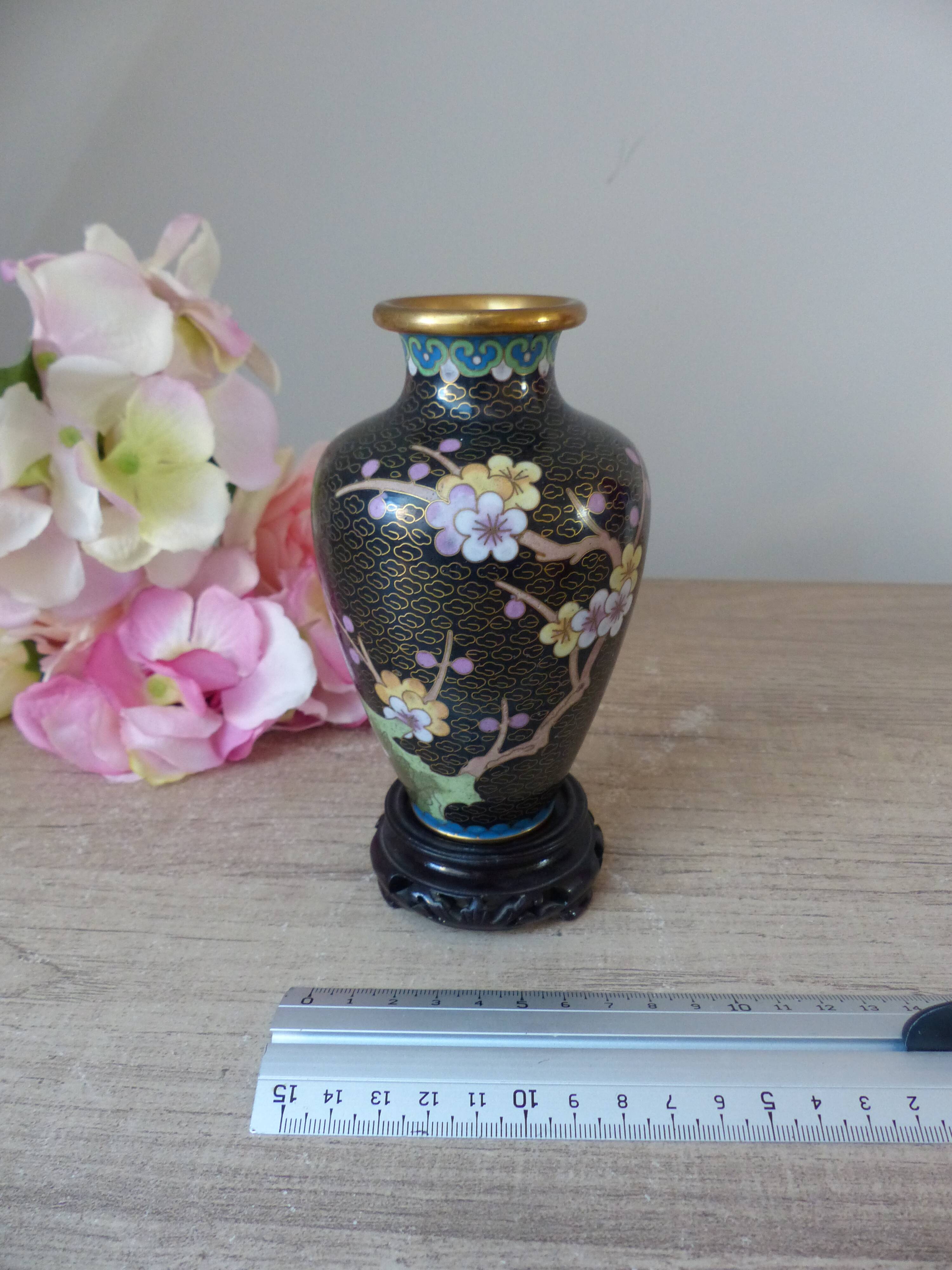 Small black cloisonné vase decorated with yellow and pink cherry blossoms, vase on wooden base