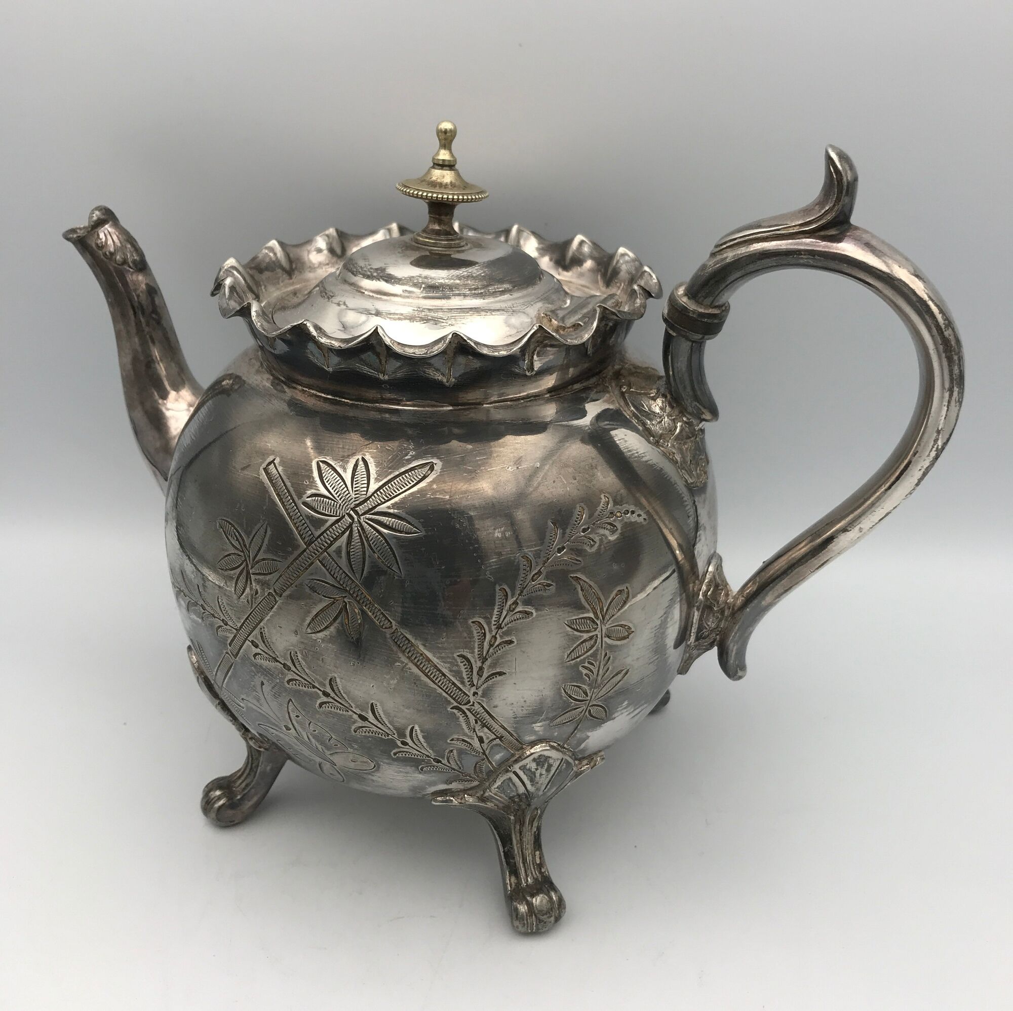 Old teapot pourer in silver metal decorated with foliage and butterflies