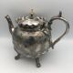 Old teapot pourer in silver metal decorated with foliage and butterflies