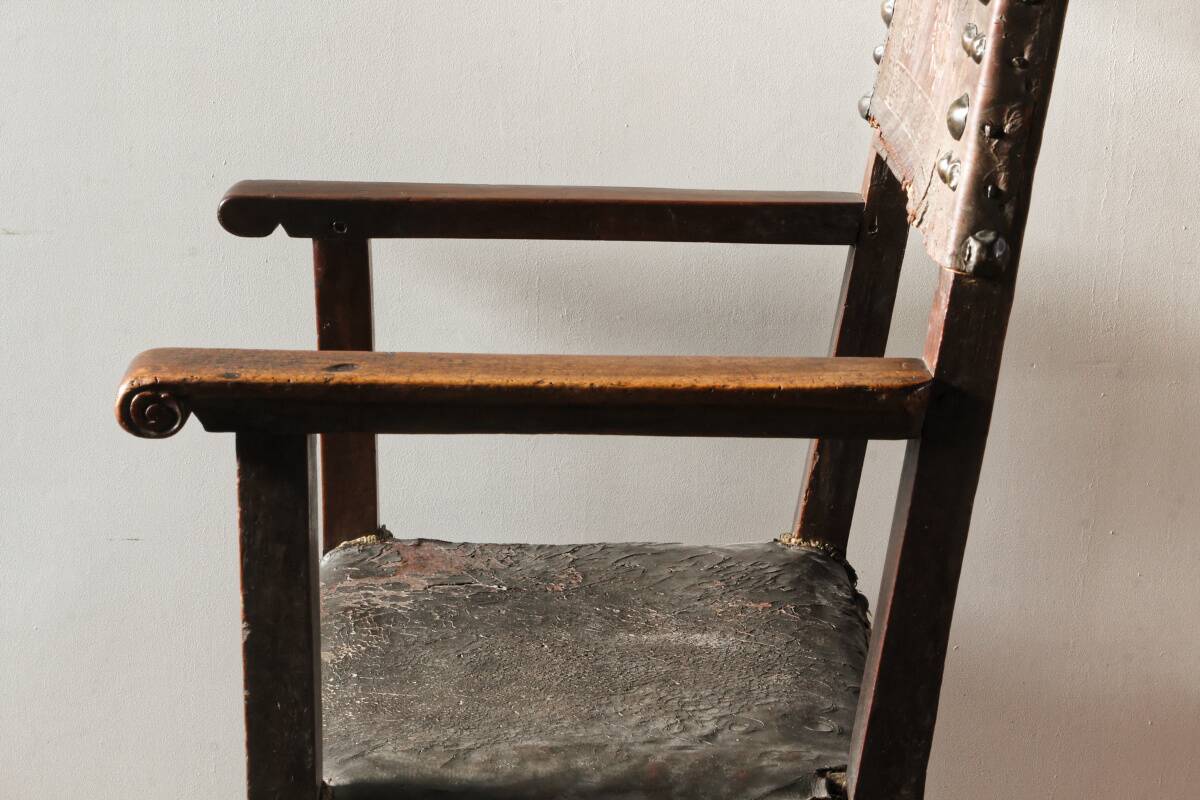 Antique armchair in walnut and studded leather, 17th century