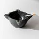 Vintage ceramic ashtray from the 1960s, black, hand-sculpted texture, organic shape.