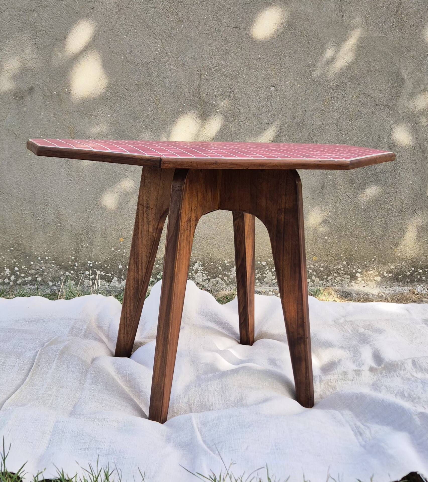 Small Scandinavian side table with wood and pink tiles, with tapered legs.
