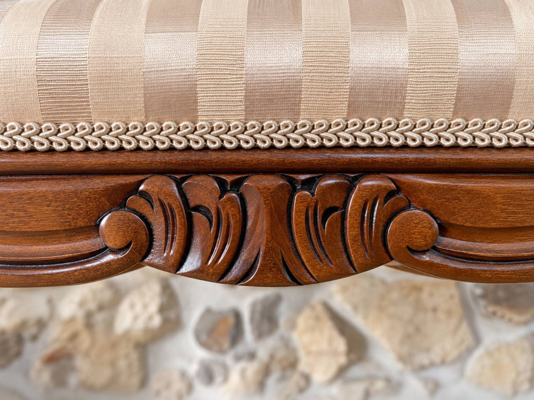 Two-seater bench in carved wood, with curved armrests.